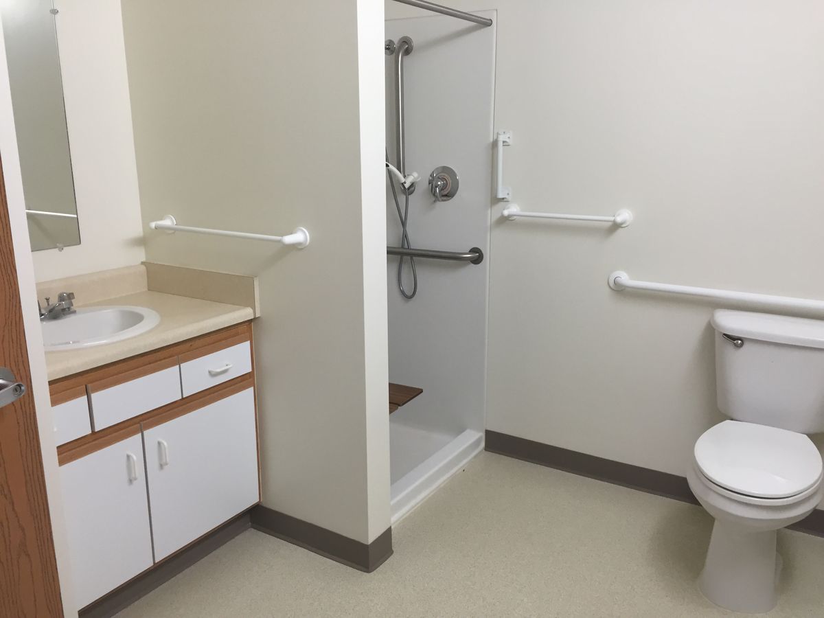 An accessible bathroom with a shower, sink, and toilet equipped with grab bars.