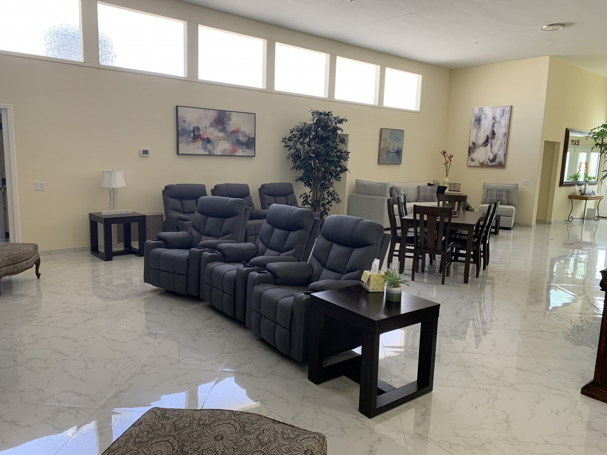 A spacious living room with recliner seating and a dining area, featuring modern decor and ample natural light.