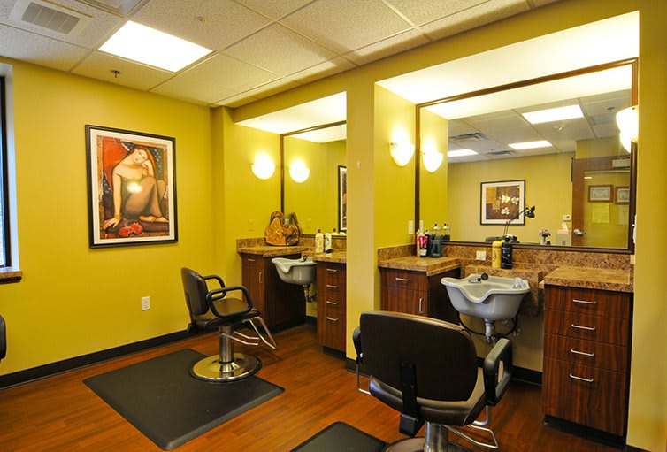 A cozy barbershop interior with chairs and mirrors, illuminated by warm lighting.