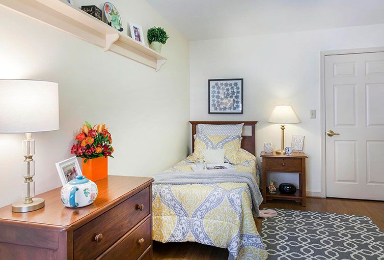 A cozy bedroom with a single bed, decorated with colorful flowers and warm lighting.