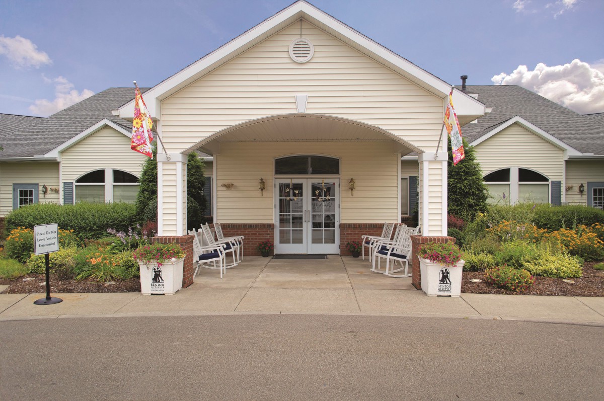 Front entrance of a building with flags and seating area.