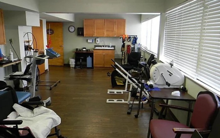 A physical therapy clinic with various exercise equipment and rehabilitation tools.