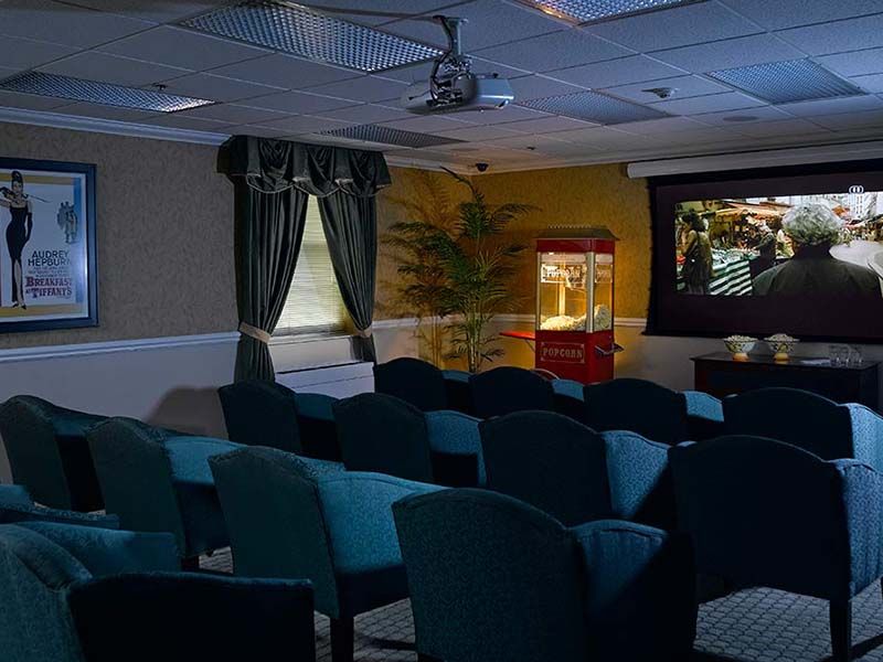 A cozy home theater room with seating, a projector screen, and a popcorn machine.