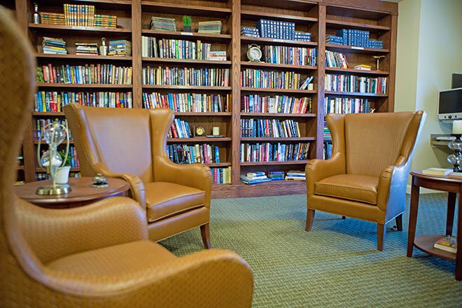 A cozy library reading area with leather armchairs and shelves filled with books.