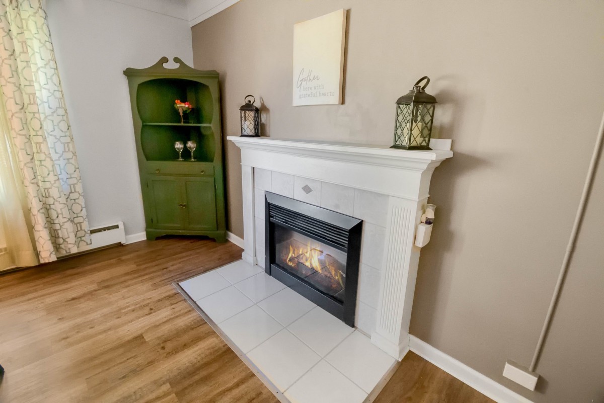 A cozy living room featuring a white fireplace with decorative lanterns and a unique green cabinet in the corner.