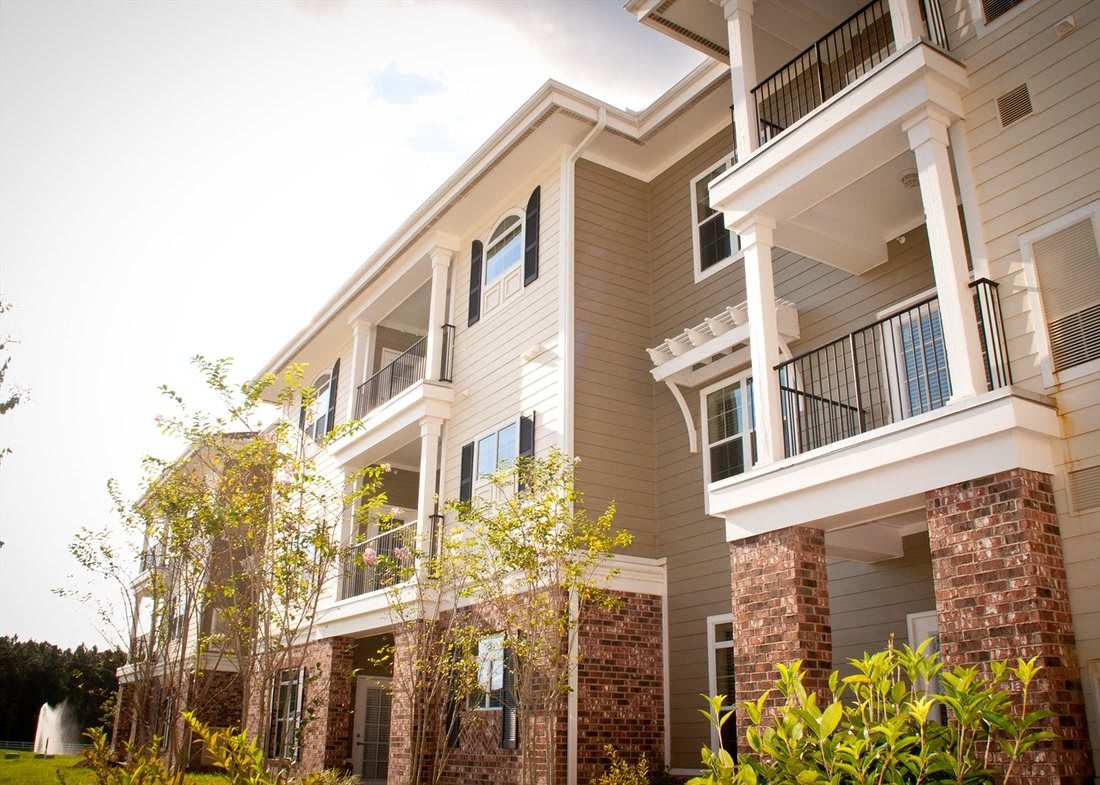 A modern apartment building with balconies and landscaped surroundings on a sunny day.