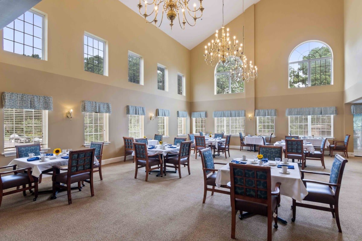 An elegant dining room with large windows, high ceilings, and chandeliers.
