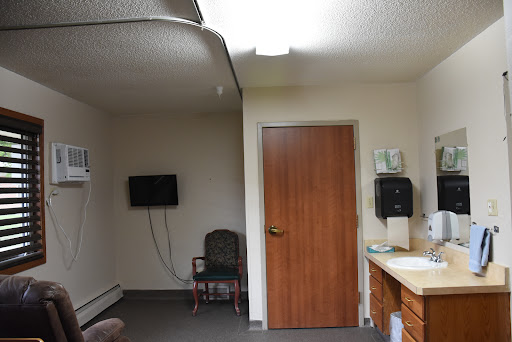 A simple waiting area in an indoor space featuring a television, a door, and basic furniture.