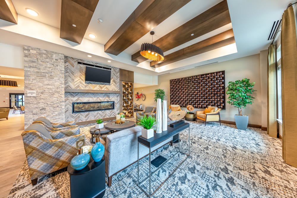 A modern and cozy living room with contemporary decor, featuring wooden ceiling beams and a patterned rug.