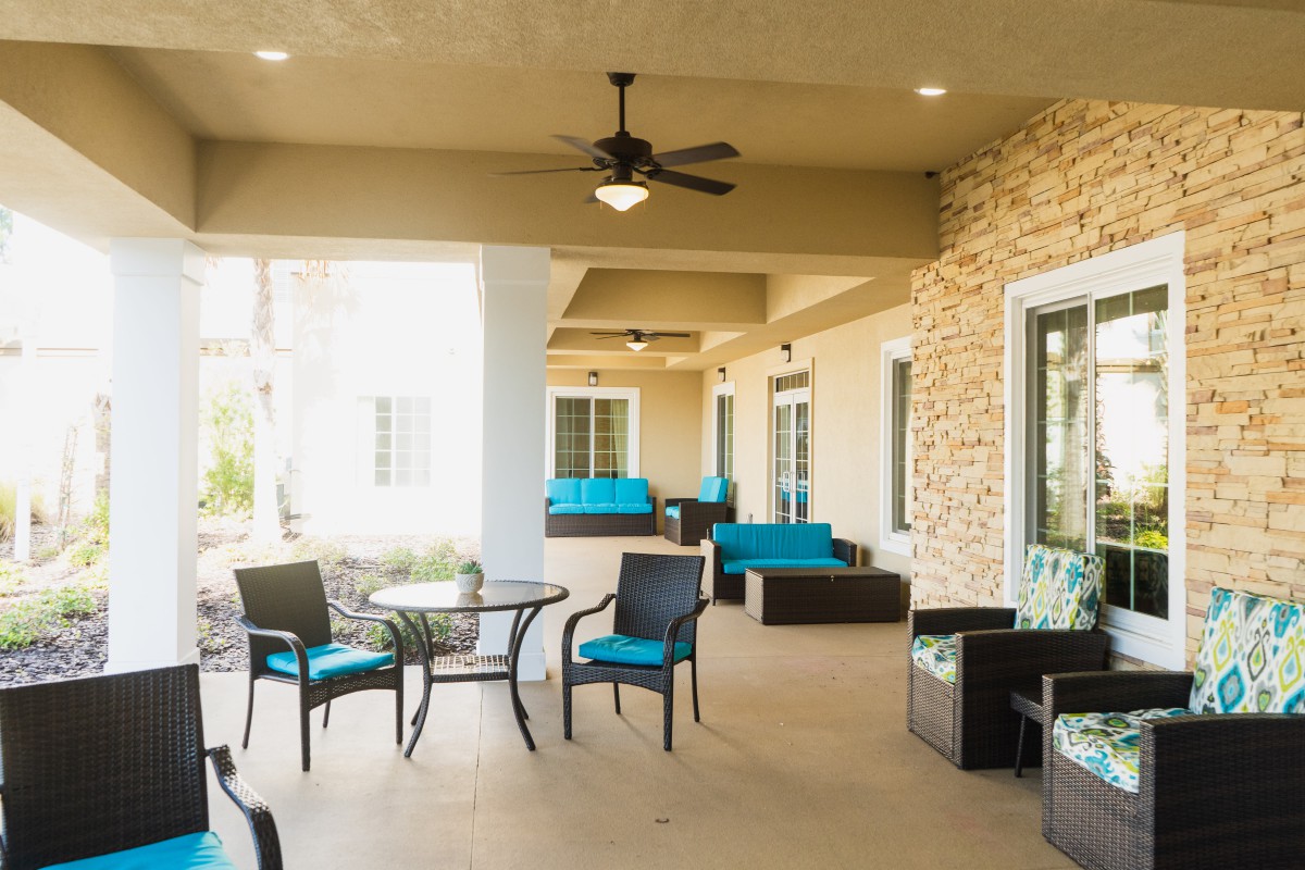 A cozy outdoor patio with modern seating and a ceiling fan.
