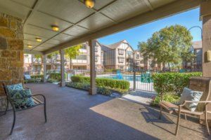 A view of an apartment complex featuring a swimming pool and landscaped outdoor area.