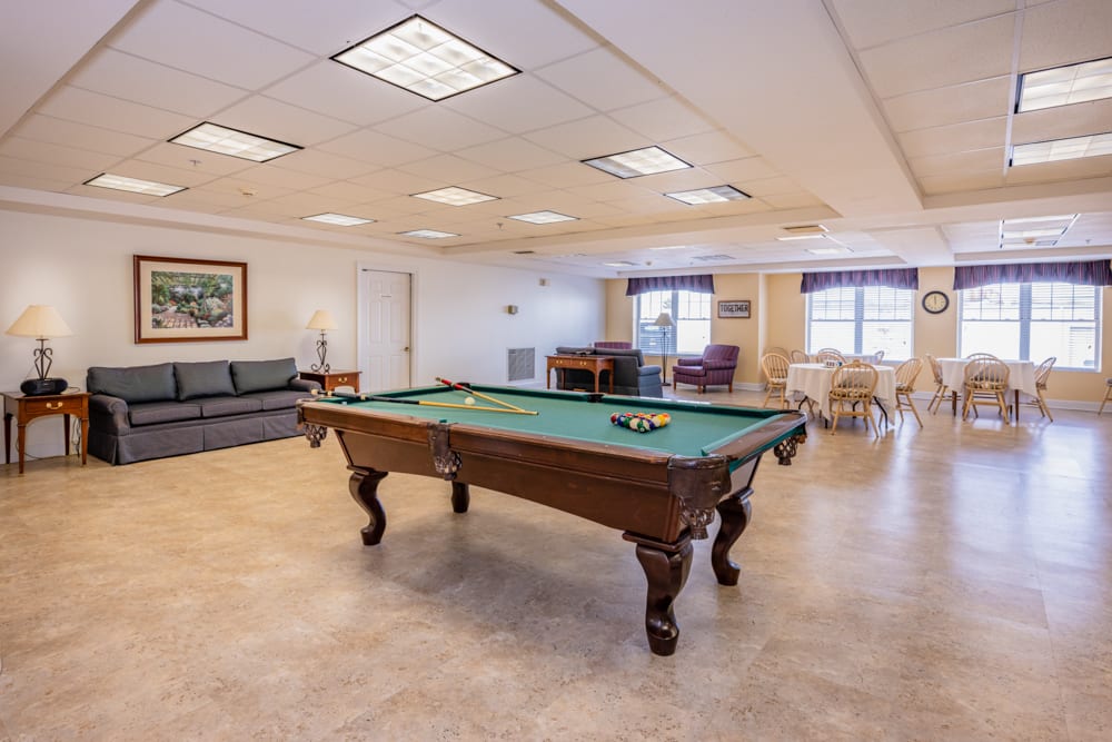 A spacious game room featuring a pool table and seating area.