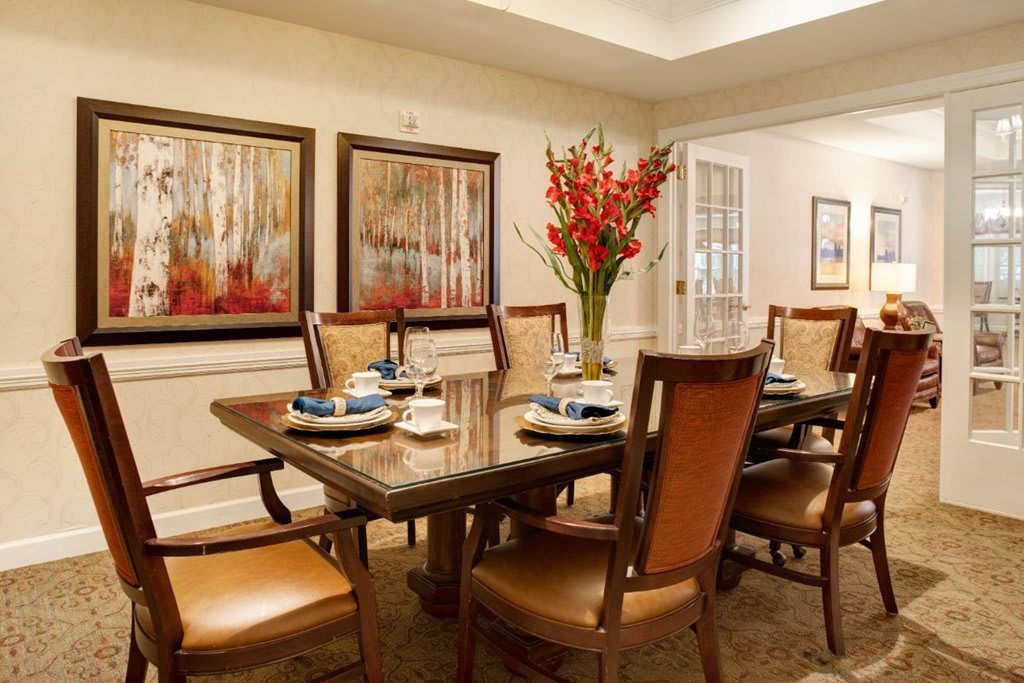 A well-decorated dining room with a large table, elegant chairs, and artwork on the walls.