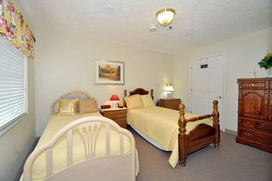 A cozy bedroom featuring twin beds with wooden frames and soft yellow bedding.