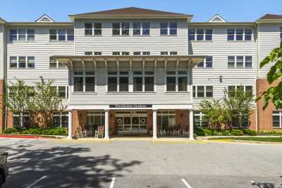A multi-story residential building with a central entrance, surrounded by trees and a parking lot.