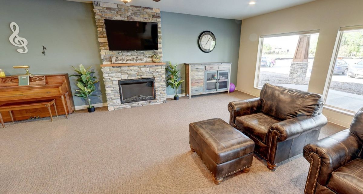 A modern living room with a stone fireplace, mounted TV, and leather seating.