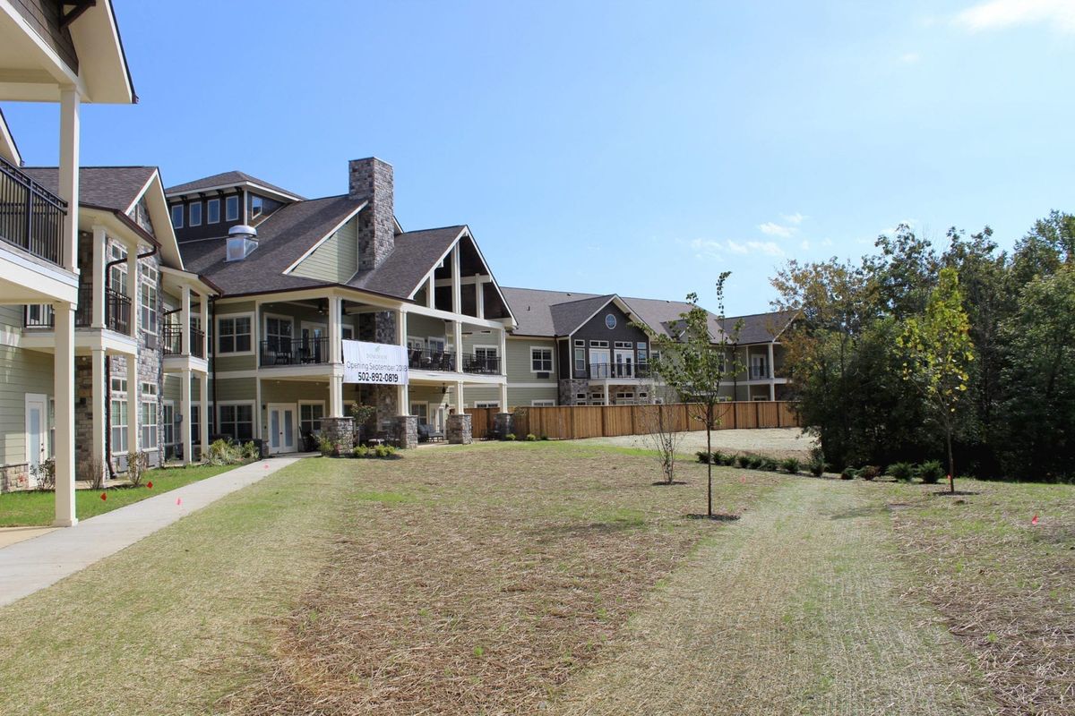 A large residential building with a spacious lawn under a clear blue sky.