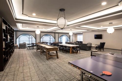 A modern and spacious game room with ping pong and seating areas.