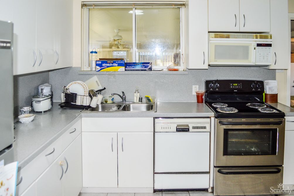 A modern kitchen featuring a stove, dishwasher, and sink with clean dishes on the countertop.