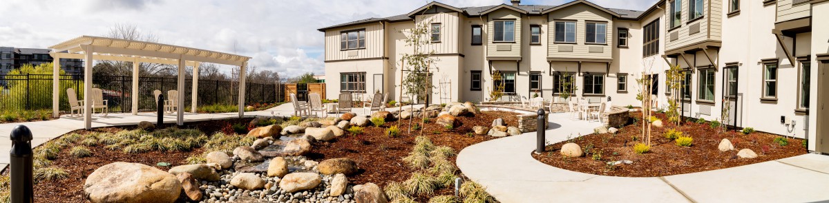 A modern home with a landscaped front yard featuring rocks and diverse plants.