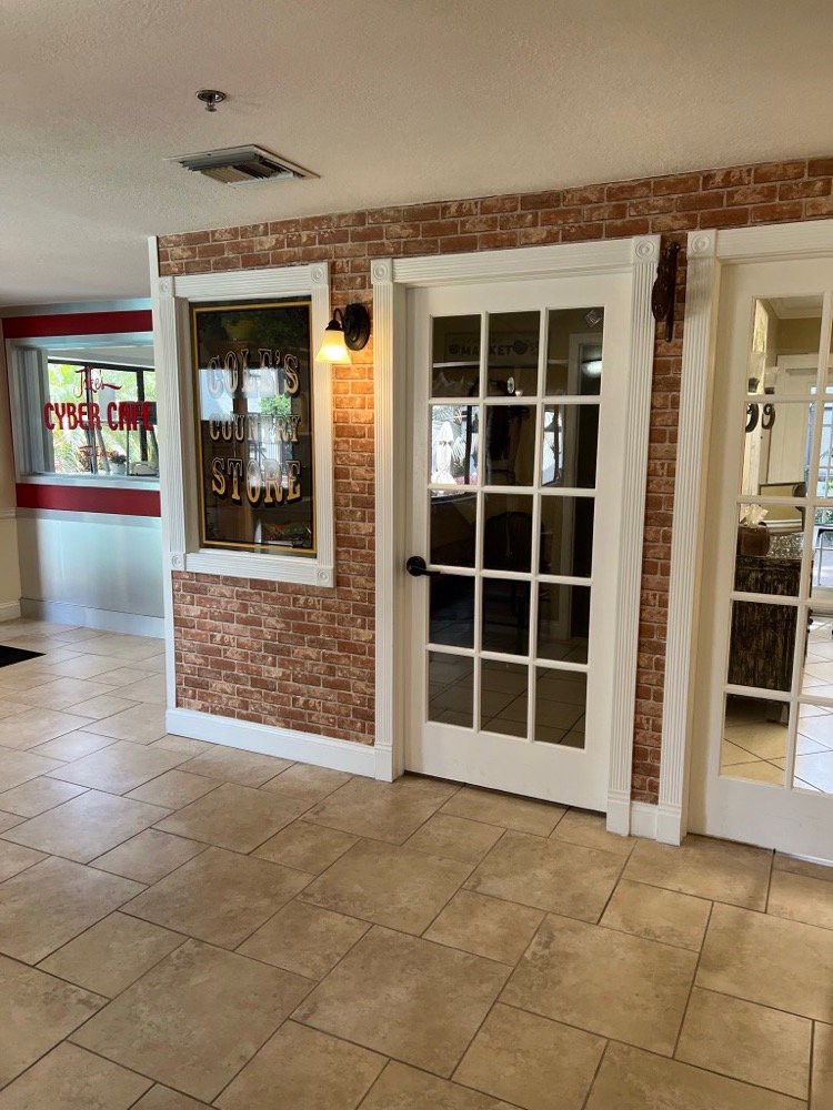 A well-lit lobby area featuring a brick accent wall and glass doors with indoor lighting.