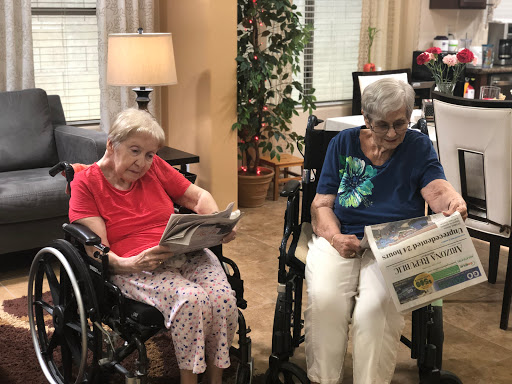 Two seniors enjoying a quiet moment together while reading newspapers in a cozy care home.