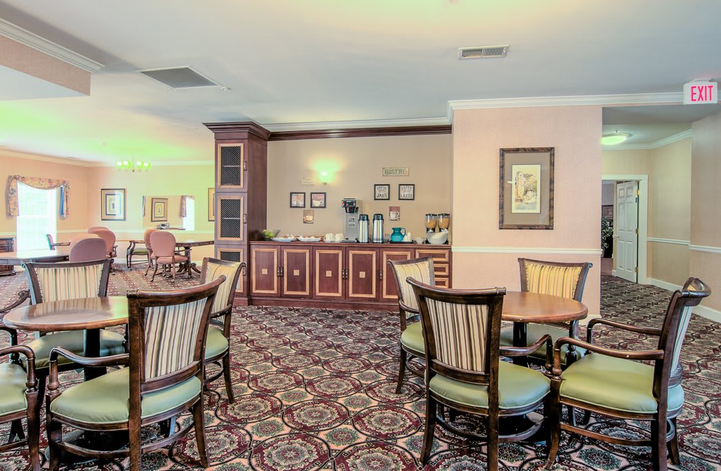 A cozy dining area with tables and chairs set on a patterned carpet.