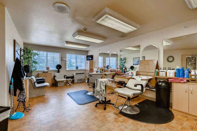 Interior of a barber shop with multiple chairs and workstations, featuring bright lighting and large mirrors.