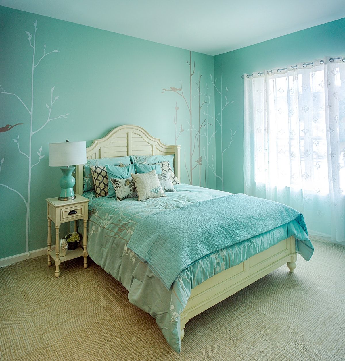 A cozy turquoise-themed bedroom with a neatly made bed and natural light filtering through the window.