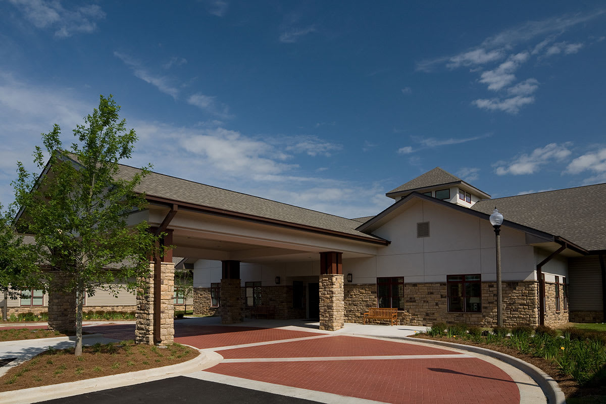 A modern building with a covered entrance and landscaped surroundings under a clear blue sky.