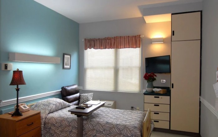 A hospital room featuring a single bed, a television, and standard medical furnishings.