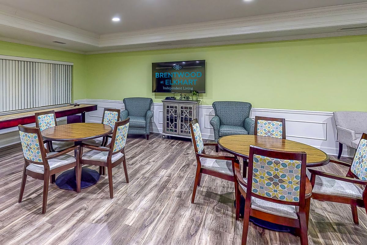 A cozy community room with tables, chairs, and a television for gatherings.