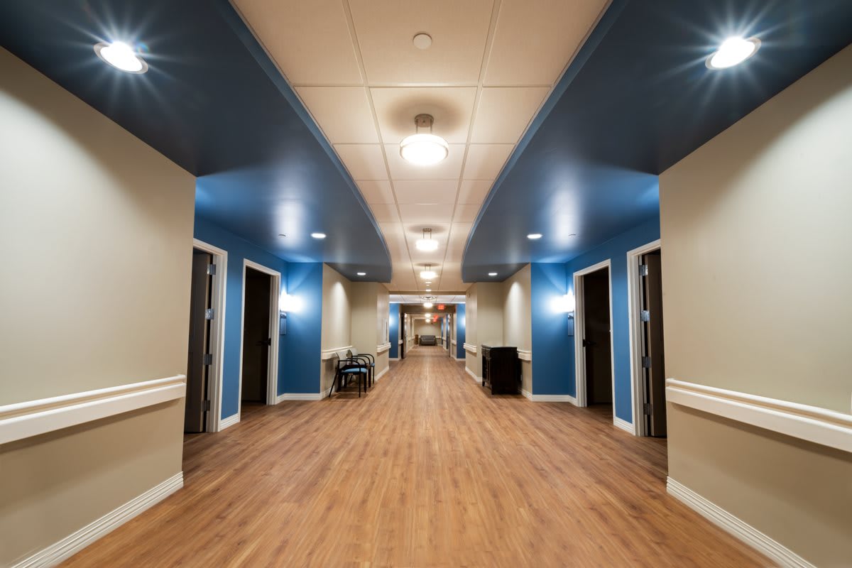 A well-lit hallway in a modern building with wooden flooring and multiple doors.