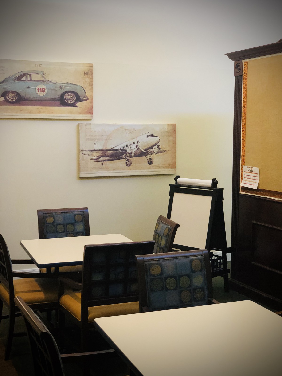 A cozy cafe interior with vintage artwork and neatly arranged seating.