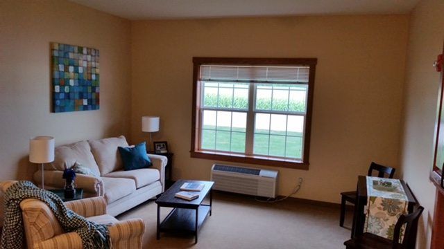 A cozy living room with a sofa, coffee table, and a large window allowing natural light.