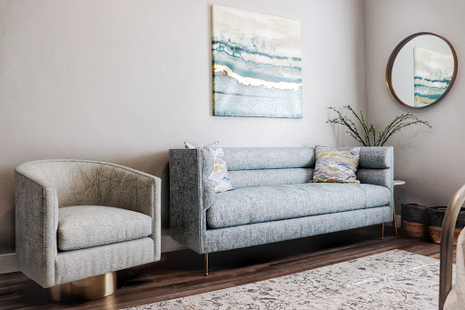A stylish living room featuring a plush gray sofa and an elegant armchair, adorned with decorative pillows and complemented by abstract wall art.
