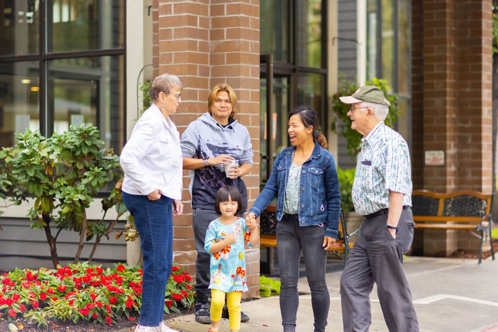 A group of people, including a child, standing outside a building and having a conversation.