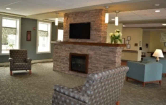 A modern living room with a central stone fireplace, TV, and comfortable seating.