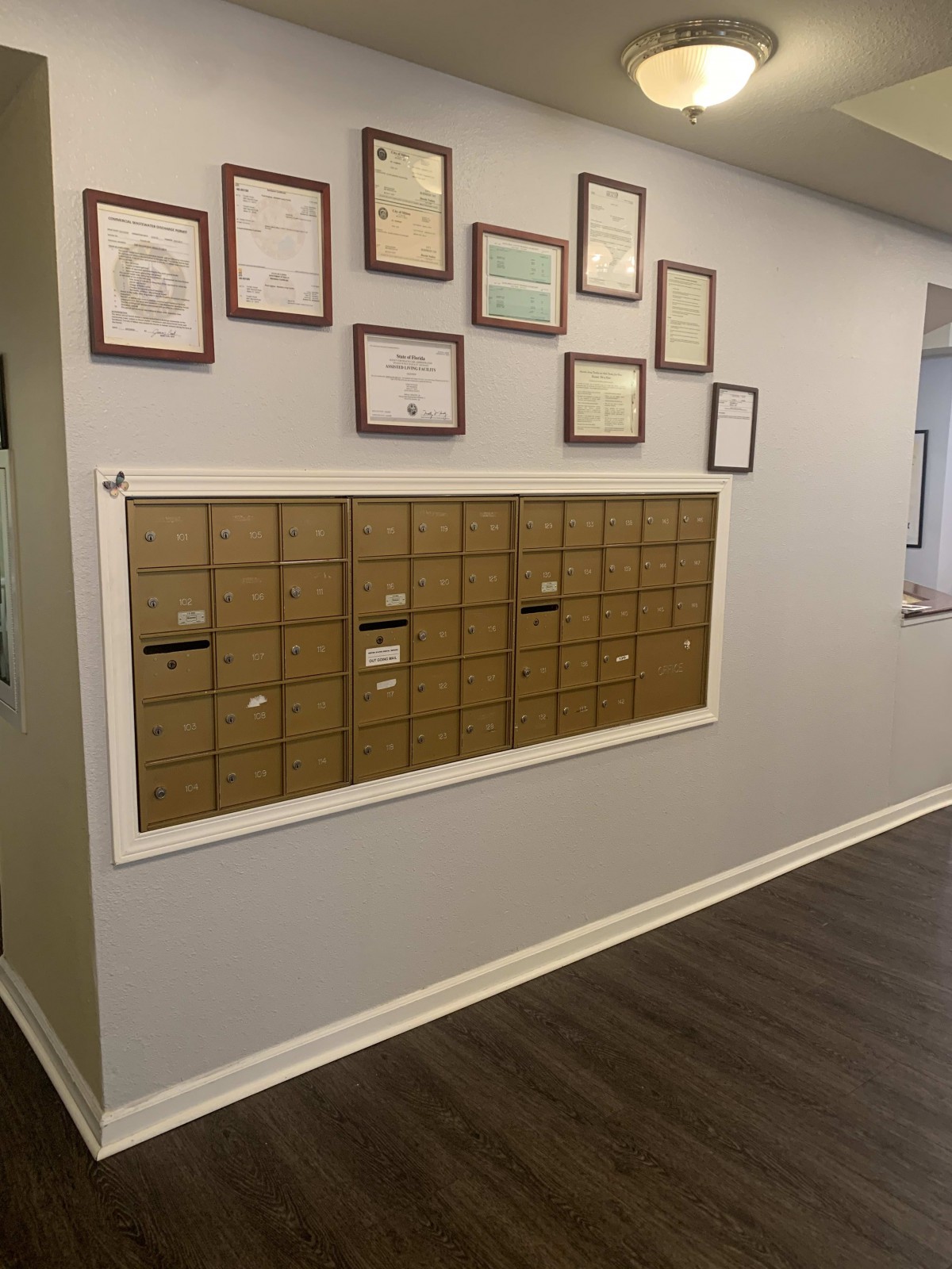A wall featuring multiple mailboxes below a display of various framed certificates.
