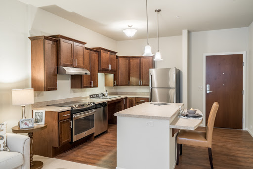 A modern kitchen featuring wood cabinets, stainless steel appliances, and an open layout.