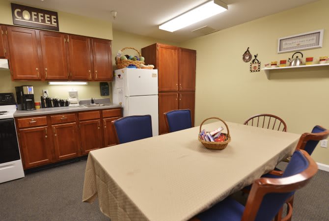 A cozy kitchen and dining area with a table, chairs, refrigerator, and wooden cabinets.