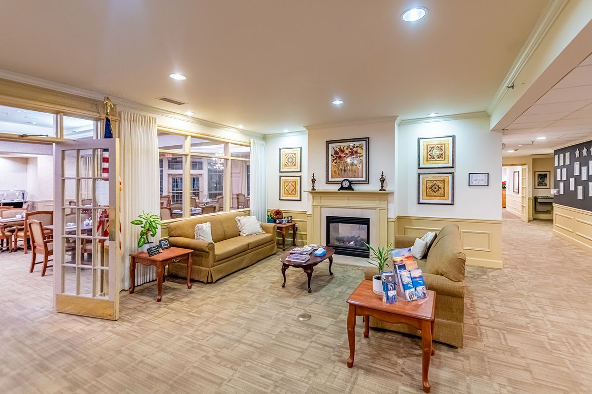 A cozy living room with sofas, a fireplace, artwork, and elegant decor.