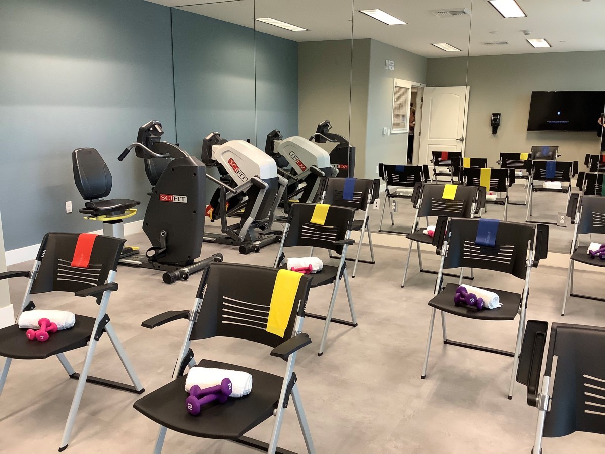 A fitness room setup with exercise bikes and rows of chairs, each equipped with a towel.