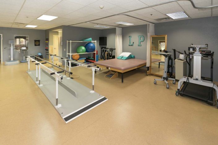 A rehabilitation room equipped with exercise equipment and parallel bars for physical therapy.