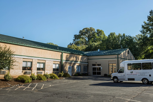 A commercial building with a green roof and a parking lot, featuring a delivery vehicle.