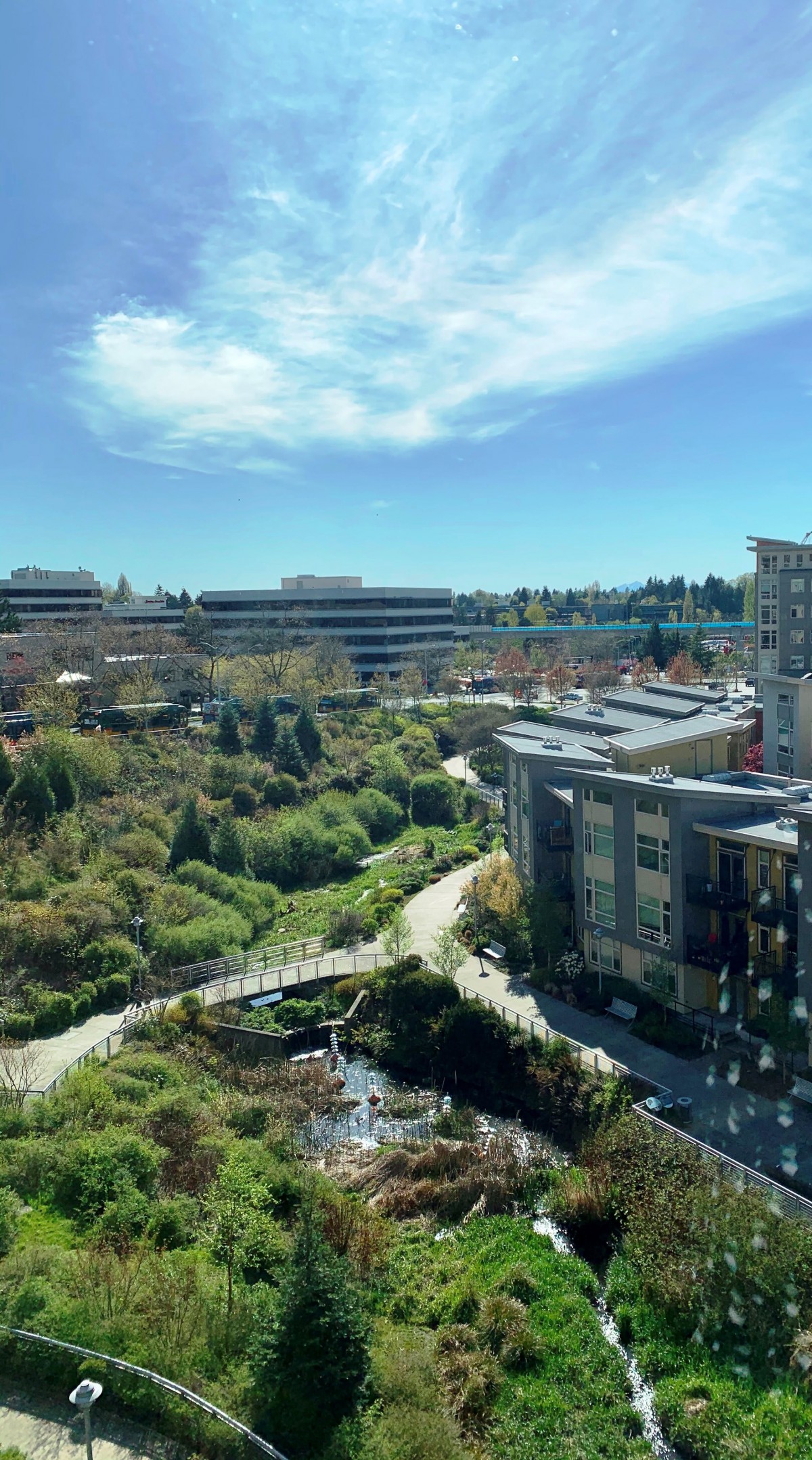 A panoramic view of a cityscape integrating modern buildings and lush greenery under a clear blue sky.