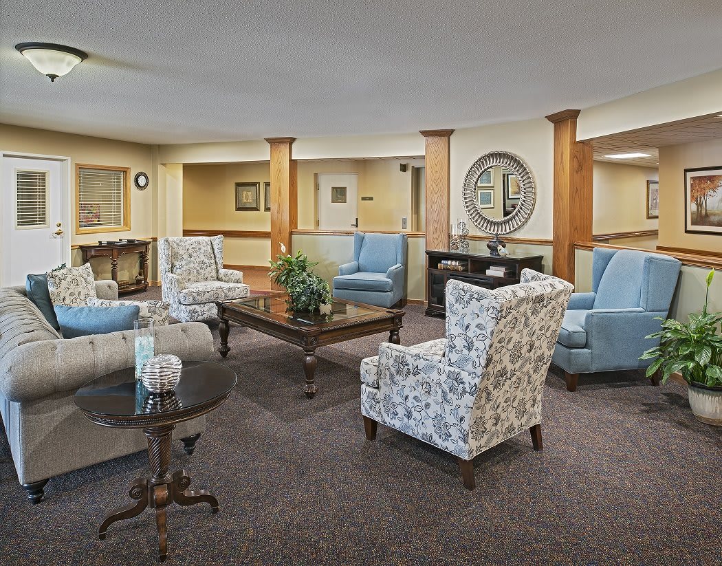 A cozy living room with a variety of armchairs and a central coffee table, decorated in neutral tones.