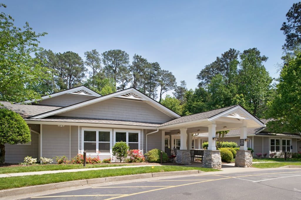 A single-story residential building with a landscaped entrance and surrounding trees.