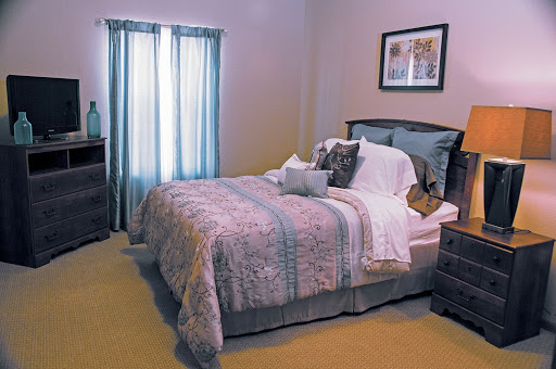 A cozy bedroom featuring a neatly made bed with decorative pillows and soft lighting from the windows.