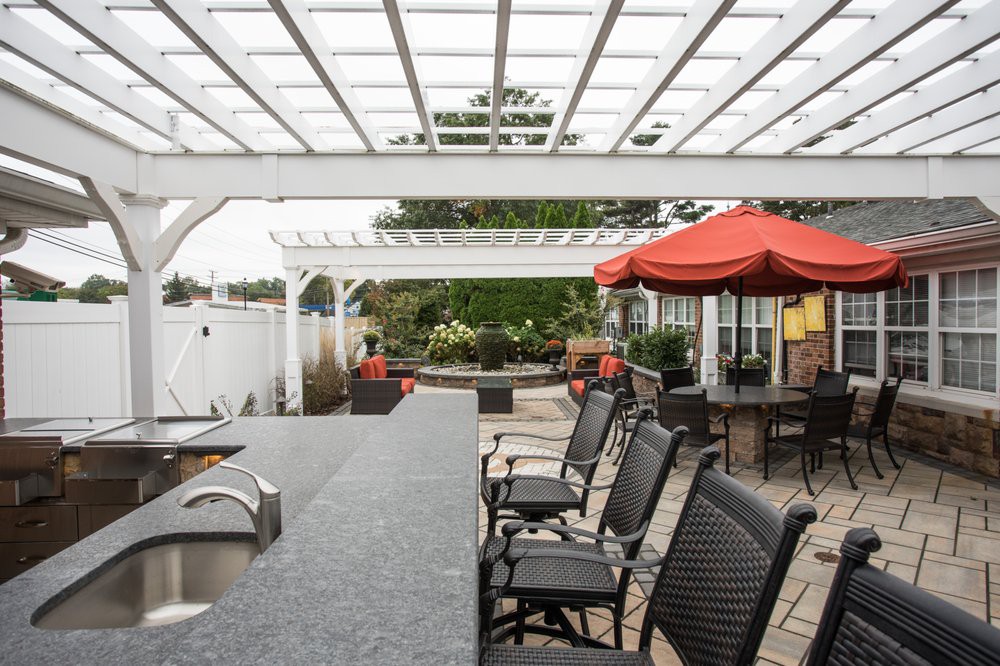 A stylish outdoor patio area with a pergola, bar seating, and umbrellas.